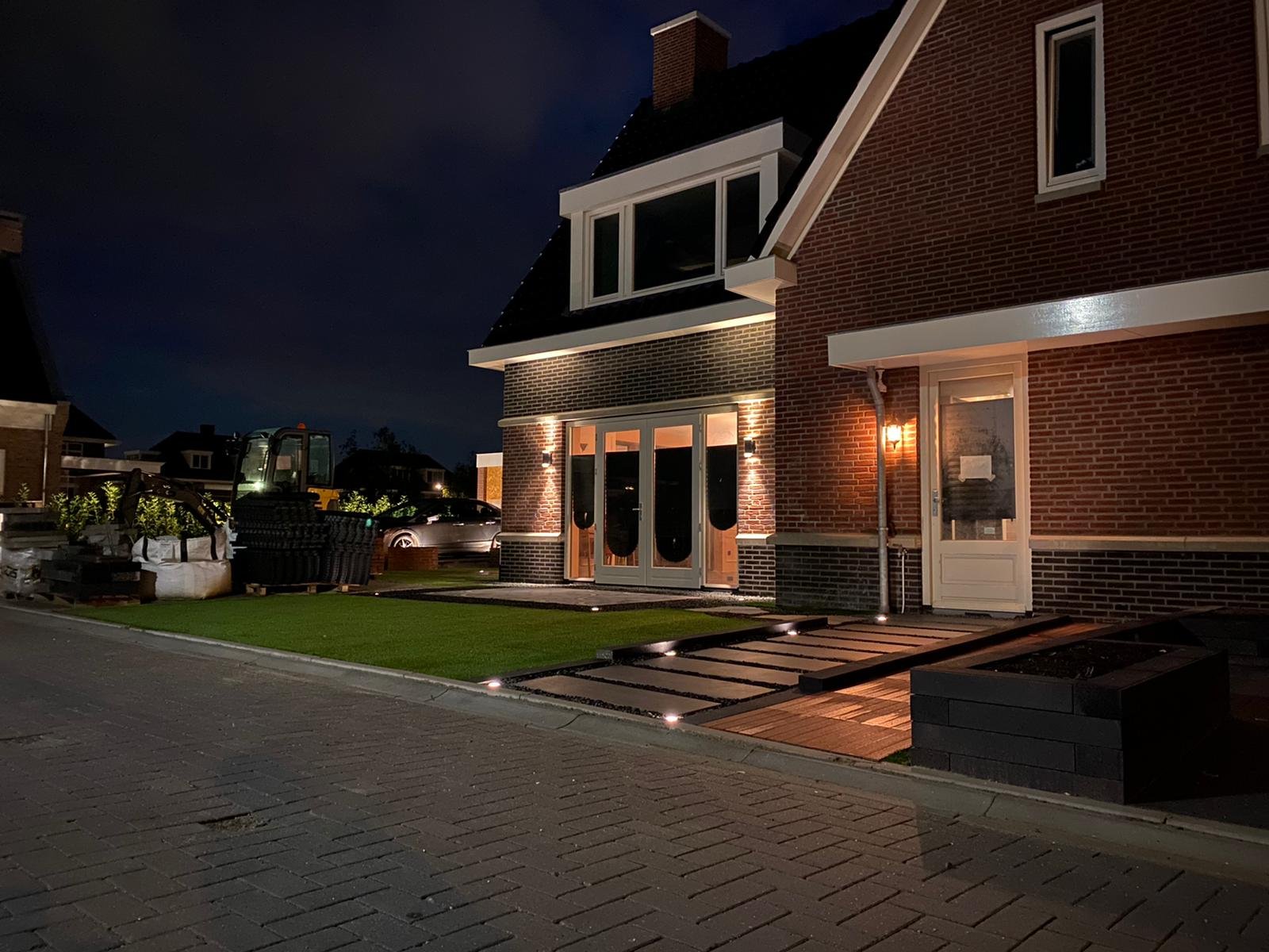Moderne buitenverlichting bij de entree en grondspots langs de oprit van een luxe villa.