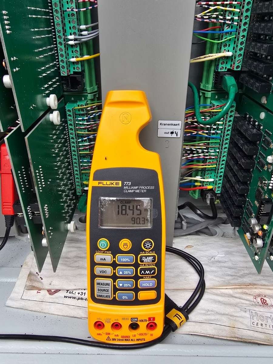 Elektromonteur voert metingen uit aan een industriële besturingskast met behulp van technische schema's en een Fluke multimeter in Den Haag.
