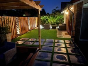 Moderne tuinverlichting met grondspots en wandlampen in een achtertuin.