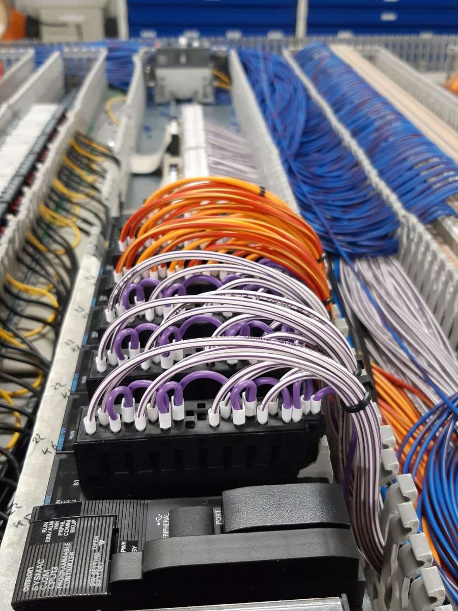 Gekleurde PLC besturingskabels en netjes weggewerkte componenten voor industriële automatisering.