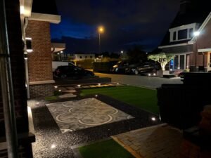 Duurzame LED grondspots die een fraai bestraat terras en gazon verlichten in de avond.