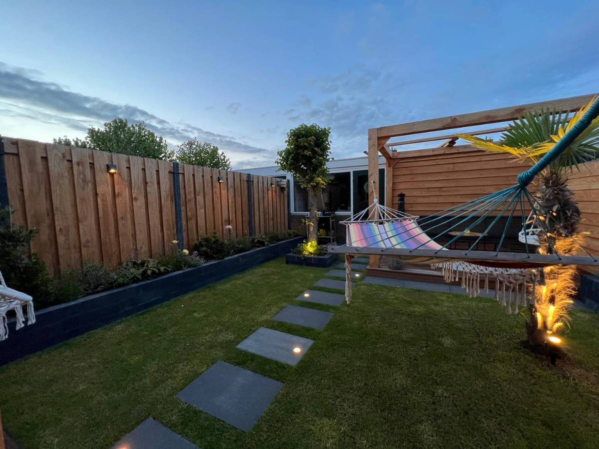 Modern tuinontwerp met warm witte LED grondspots verwerkt in grote terrastegels.