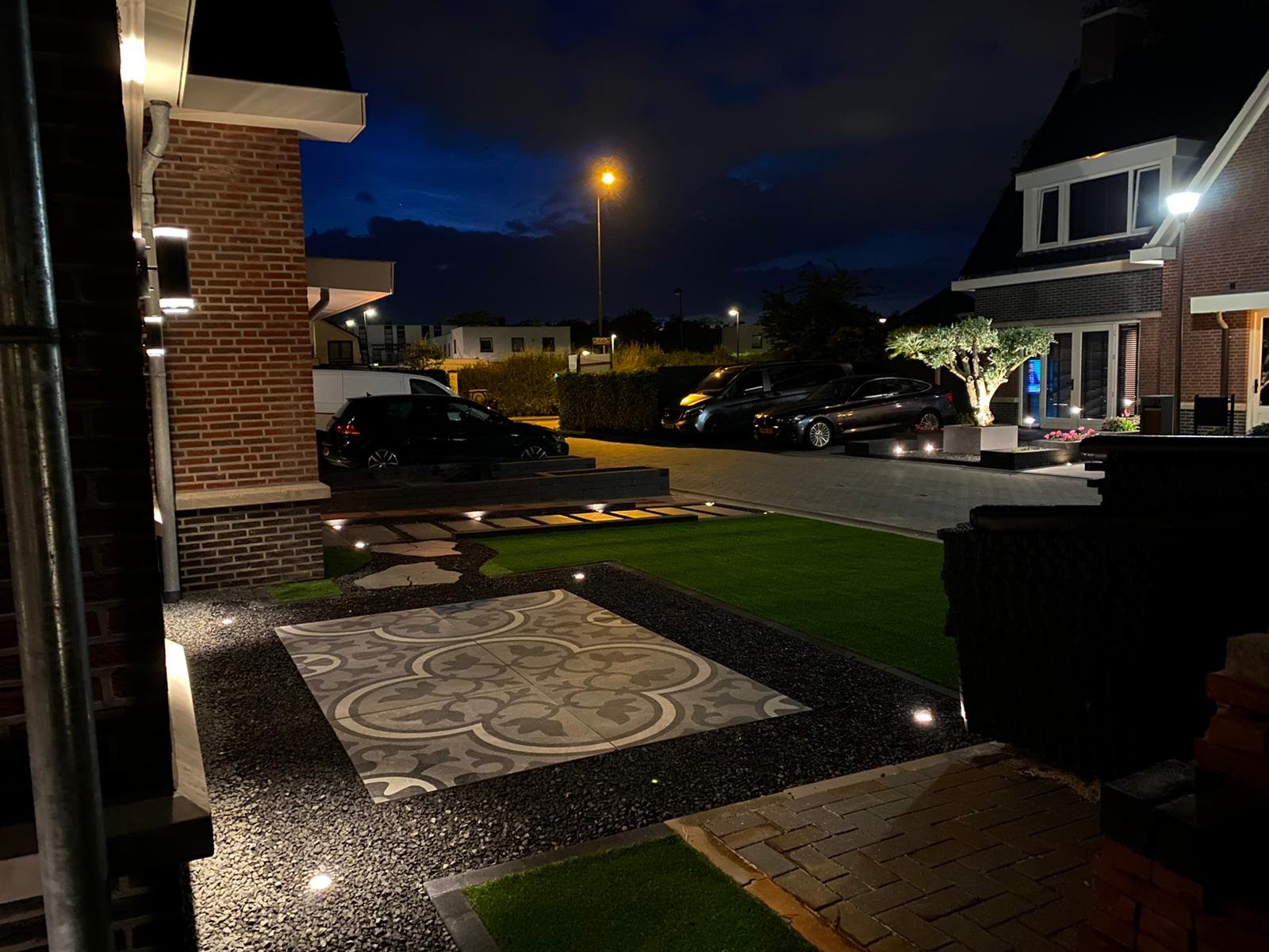 Duurzame LED grondspots die een fraai bestraat terras en gazon verlichten in de avond.