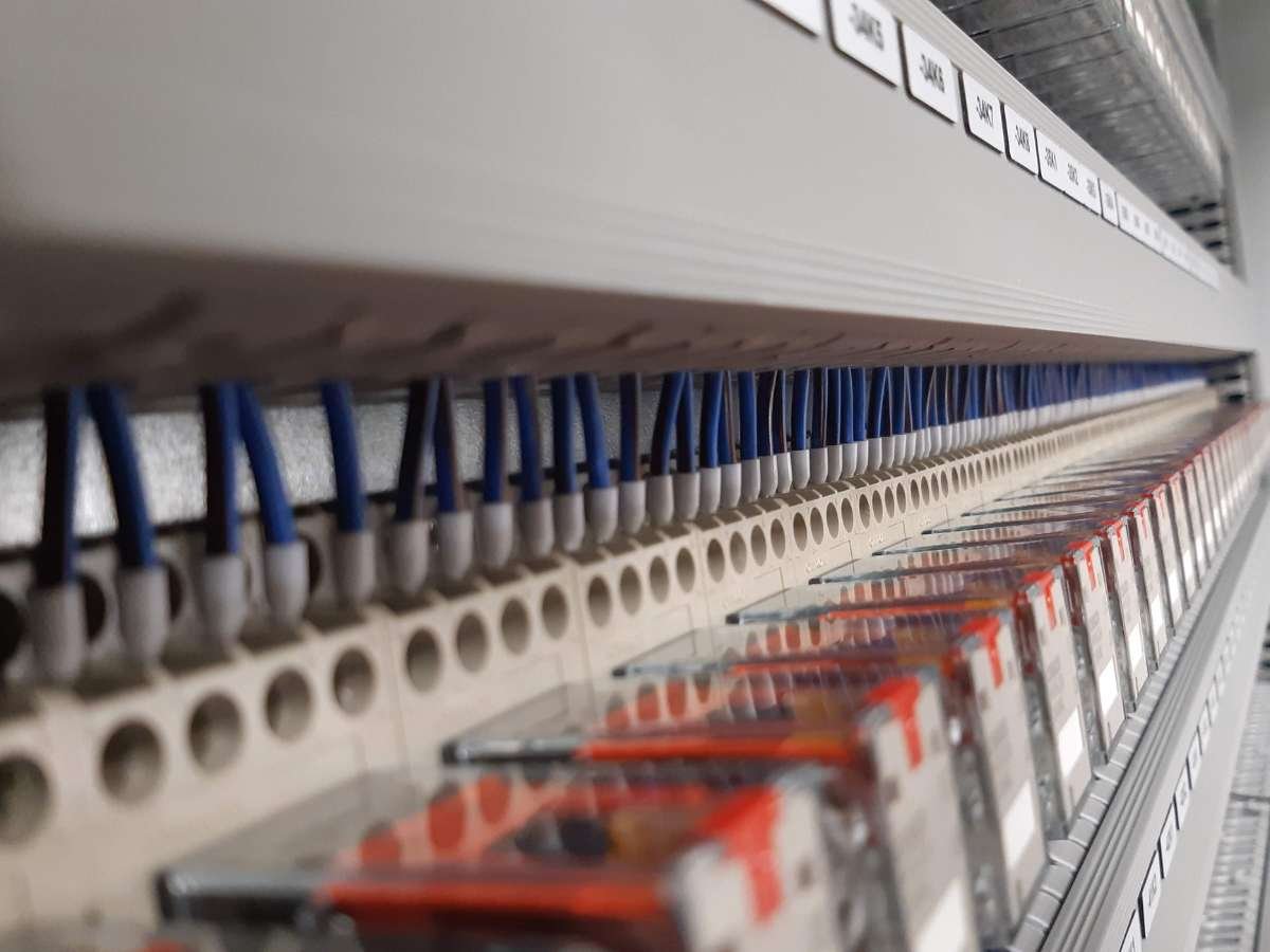 Detailweergave van professionele componenten en blauwe bedrading in een schakelkast.