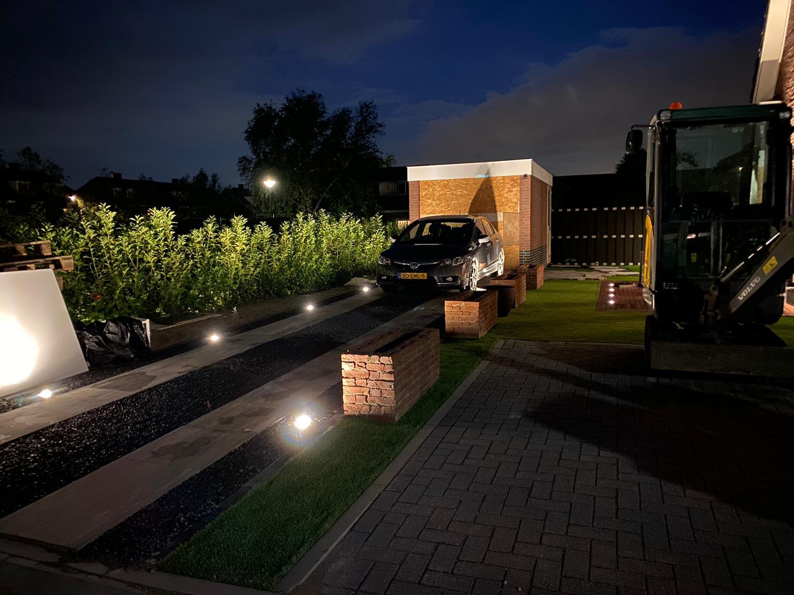 Functionele opritverlichting met grondspots gericht op de haagbeplanting en parkeerplaats.