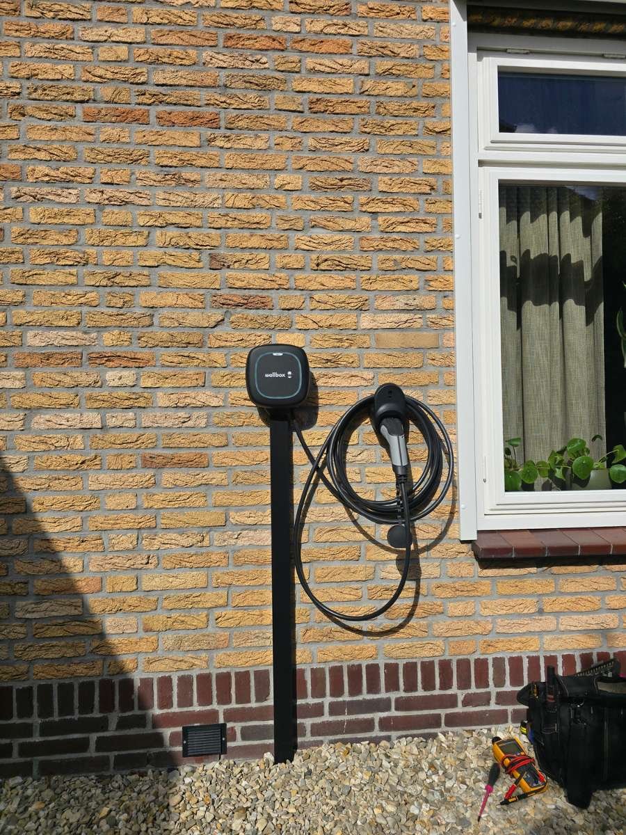 Laadpaal montage aan een bakstenen muur voor een elektrische auto in Den Haag.